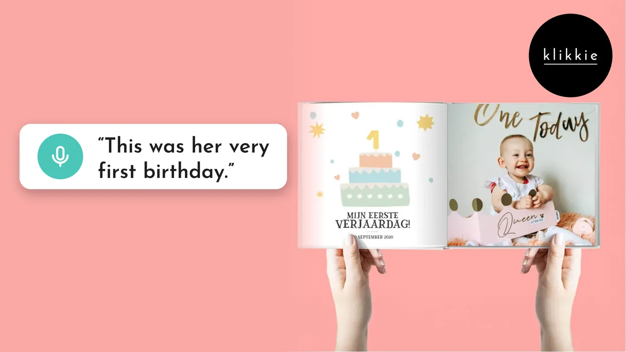Des mains tiennent un livre photo klikkie My First Year ouvert sur le premier anniversaire, avec les mots « This was her very first birthday. »